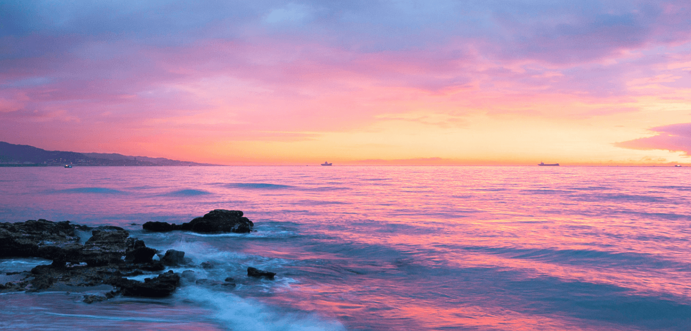 A sunrise at the ocean, over looking short swells.